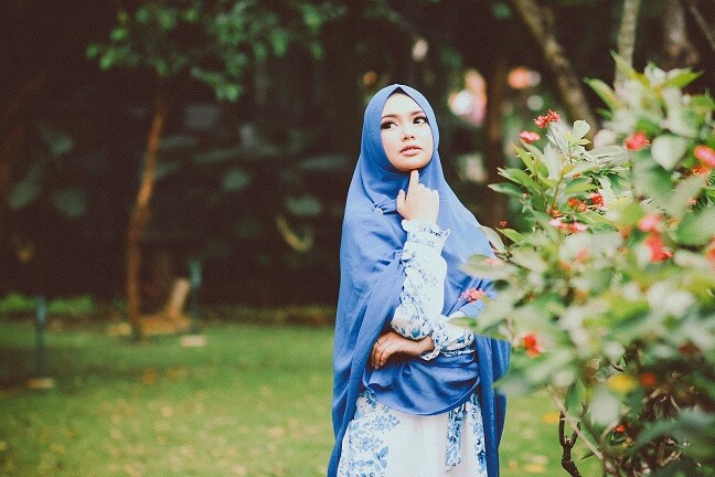 Muslimisches mädchen, das in einem park etwas in blauer kleidung betrachtet
