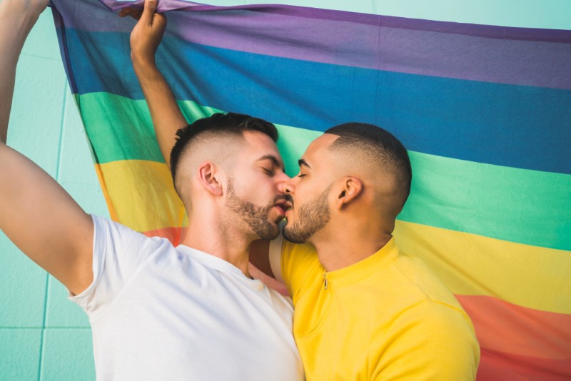 Zwei schwule männer küssen sich vor einer regenbogenflagge